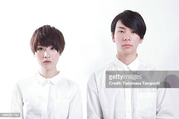 young couple standing to look straightforward - ausdruckslos stock-fotos und bilder