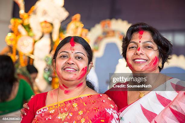 women applying ritualistic vermilion on each other during durga puja - bengali sari stockfoto's en -beelden