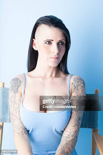 tattooed girl wearing a pastel blue dress - regisseurstoel stockfoto's en -beelden