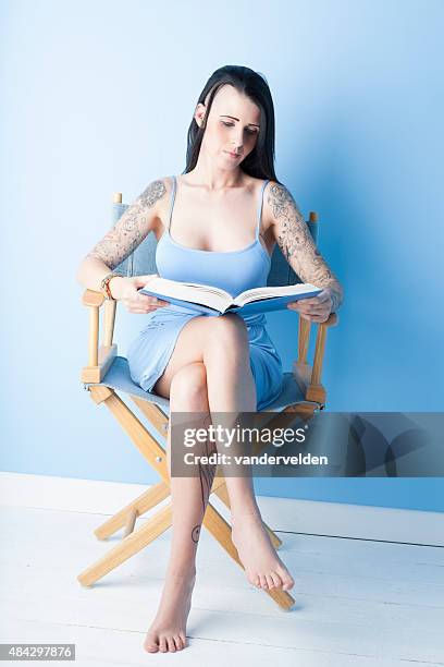 tattooed girl wearing a pastel blue dress - regisseurstoel stockfoto's en -beelden