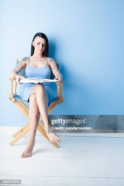 tattooed girl wearing a pastel blue dress - regisseurstoel stockfoto's en -beelden