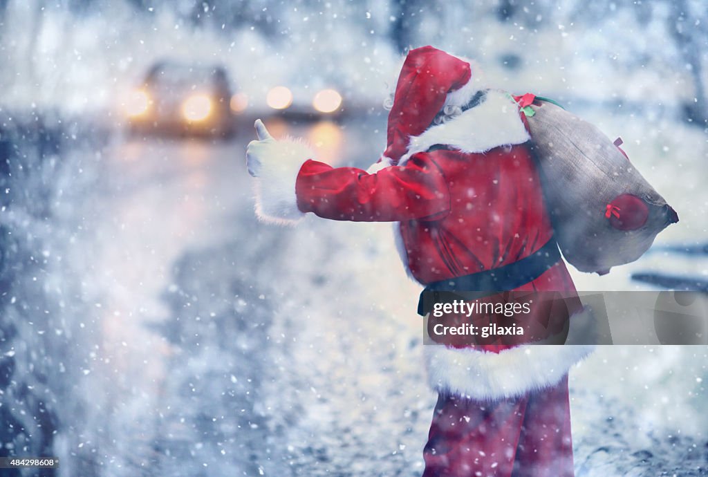 Santa Claus hitchhiking on a snowy day.