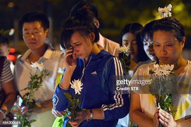 This picture taken on August 16, 2015 shows residents holding flowers at the crossroads outside Tianjin Taida hospital at a vigil for the victims of...