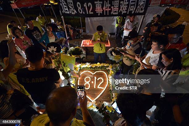 This picture taken on August 16, 2015 shows residents taking photos of lit candles at the crossroads outside Tianjin Taida hospital at a vigil for...