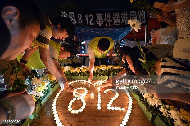 This picture taken on August 16, 2015 shows residents lighting candles at the crossroads outside Tianjin Taida hospital at a vigil for the victims of...