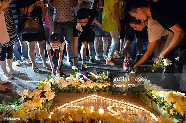 This picture taken on August 16, 2015 shows residents laying flowers around candles at the crossroads outside Tianjin Taida hospital at a vigil for...