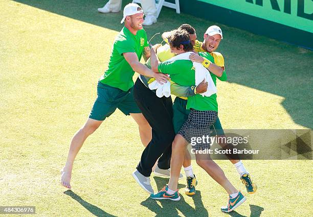 Sam Groth, Thanasi Kokkinakis and Nick Kyrgios run on court to congratulate teammate Lleyton Hewitt of Australia as he celebrates winning the reverse...