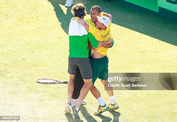 Sam Groth, Thanasi Kokkinakis and Nick Kyrgios run on court to congratulate teammate Lleyton Hewitt of Australia as he celebrates winning the reverse...