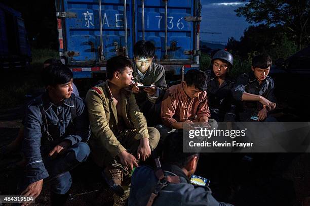 Chinese actors watch films on their mobile phones during a break in the filming of a battle segment in a series set during the second Sino-Japanese...