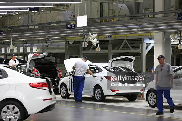 Workers inspect completed Kia Rio, top left, and Hyundai Solaris vehicles, center, at the end of the production line at the Hyundai Motors Corp....