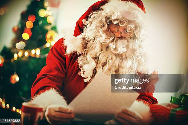 santa claus reading letters and wishlists. - wish list stock pictures, royalty-free photos & images