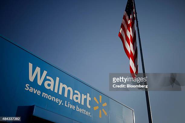 An American flag flies near signage displayed outside of the Wal-Mart Stores Inc. Headquarters building in Bentonville, Arkansas, U.S., on Wednesday,...