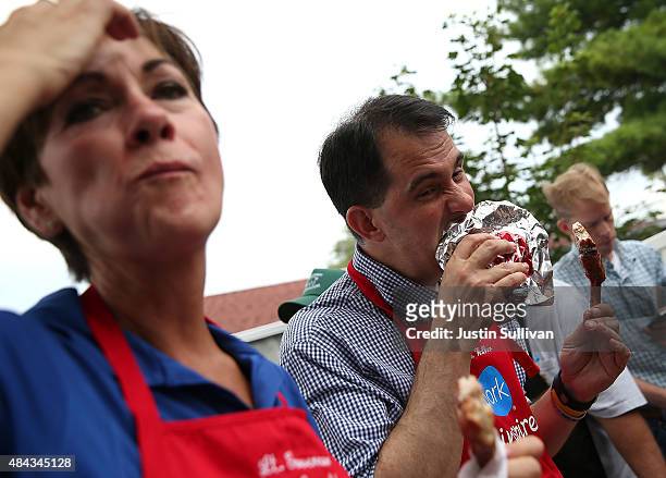 Republican presidential candidate and Wisconsin Gov. Scott Walker bites into a pork chop at the Iowa Pork Producers Pork Tent as Iowa Lt. Gov. Kim...