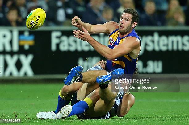 Jack Darling of the Eagles handballs whilst being tackled by Jared Rivers of the Cats during the round four AFL match between the Geelong Cats and...