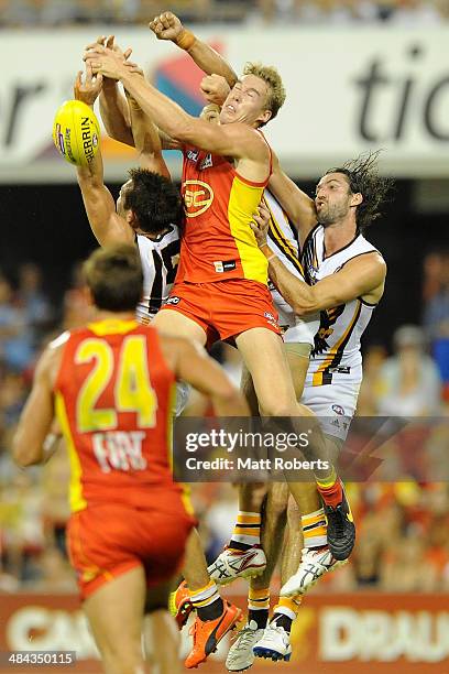 Tom Lynch of the Suns competes for the mark Luke Hodge and Matt Spangher of the Hawks during the round four AFL match between the Gold Coast Suns and...