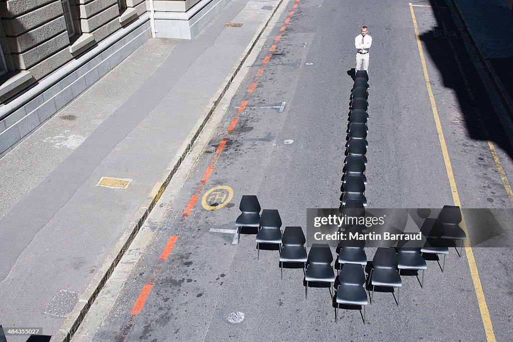 Businessman standing at office chair in arrow-shape