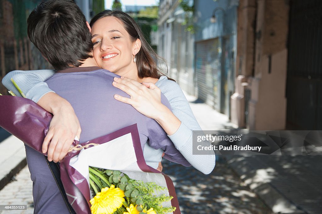 Couple embracing outdoors with flowers smiling