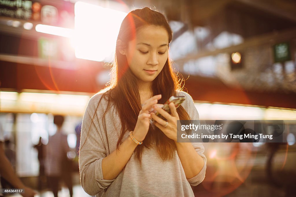 Young lady using smartphone on train platform