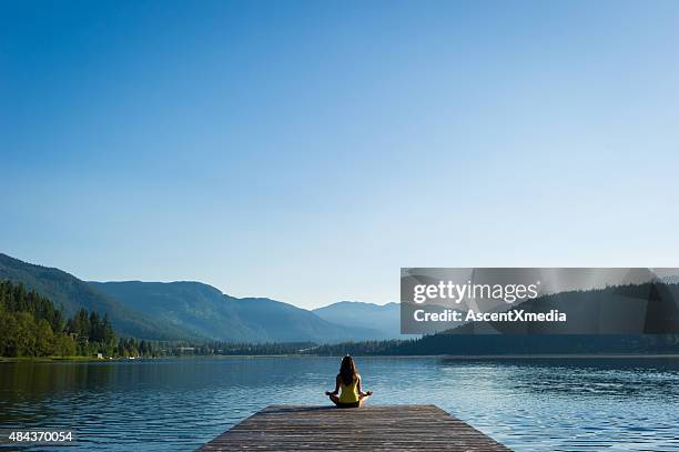 pose fácil tranquila lakeside meditação ao nascer do sol - budismo imagens e fotografias de stock