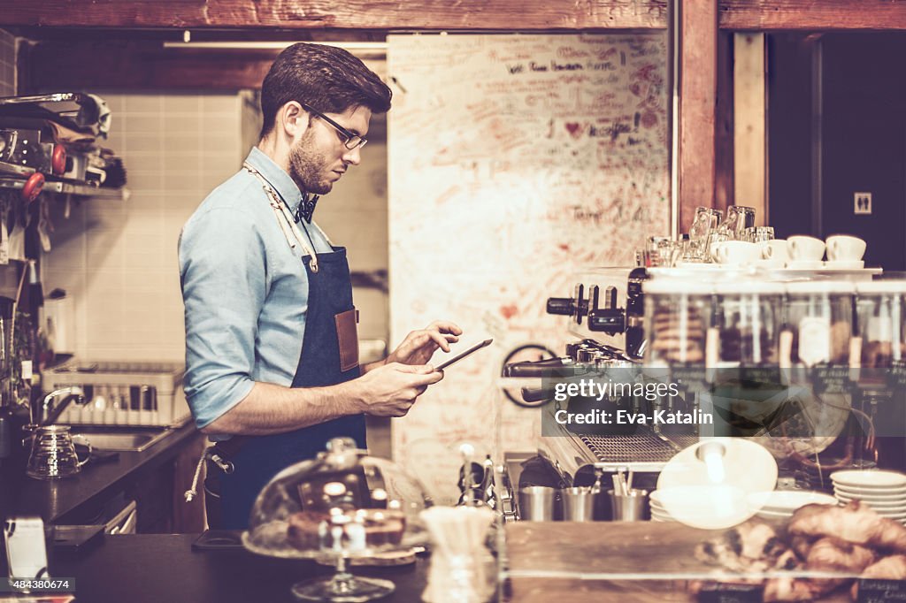 Giovane barista sta usando un digital tablet