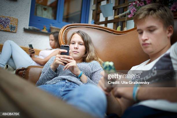 Germany Youth sitting on a couch staying outside in the garden playing with their cellphones. On August 10, 2015 in Bonn, Germany.