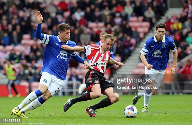 Lee Cattermole of Sunderland is harried by Ross Barkley of Everton with Gareth Barry watching on during the Barclays Premier League match between...