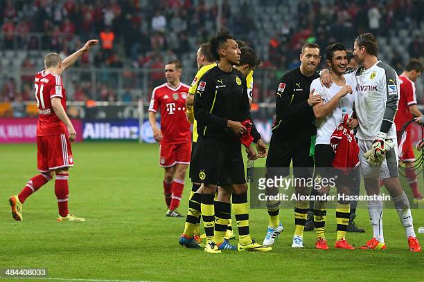 Bastian Schweinsteiger of Muenchen and his team mate Philipp Lahm walk over the field whilst Roman Weidenfeller of Dortmund celebrates victory with...