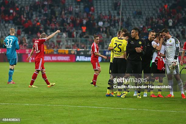 Bastian Schweinsteiger of Muenchen and his team mates Lukas Raeder and Philipp Lahm walk over the field whilst Roman Weidenfeller of Dortmund...