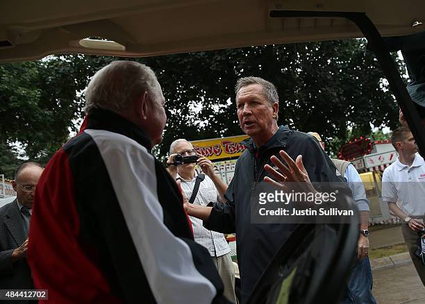 Republican presidential candidate and Ohio Gov. John Kasich talks with a fairgoer as he tours the Iowa State Fair on August 18, 2015 in Des Moines,...