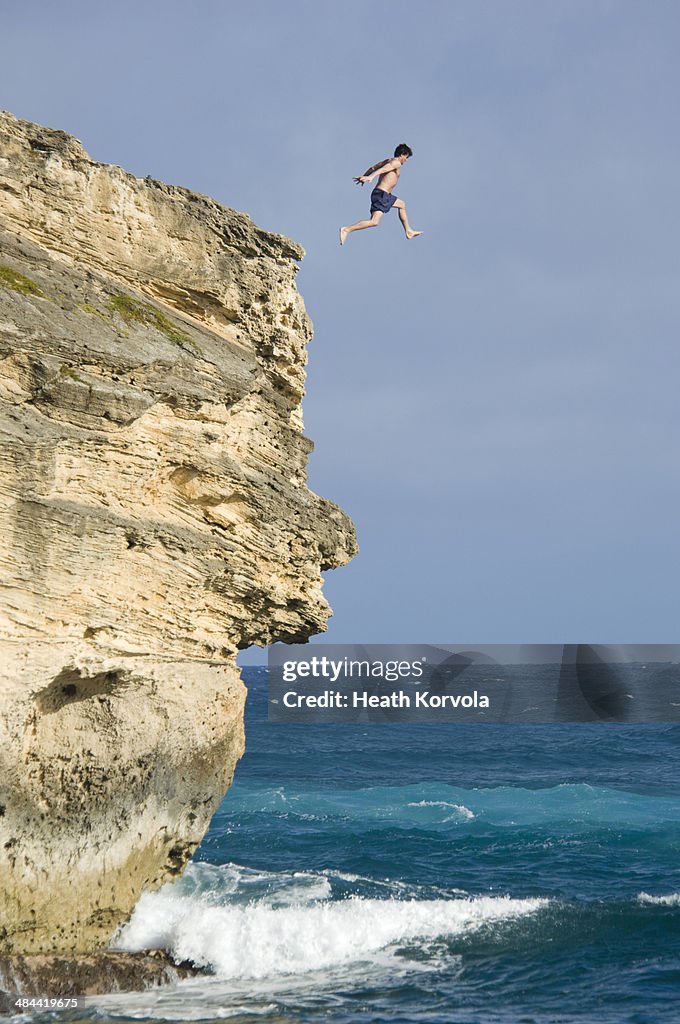 Man leaps off tall cliff into ocean.