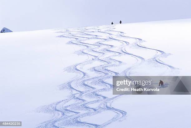 backcountry skier matching tracks downhill. - pista de esquí fotografías e imágenes de stock