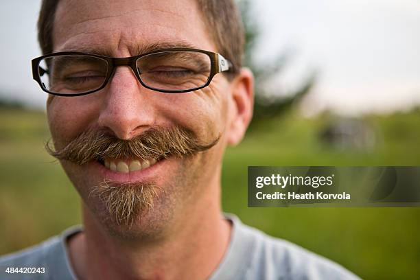 a mustached-man dons a smile in a field. - moustaches stockfoto's en -beelden