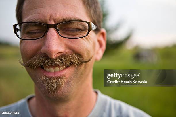 a mustached-man dons a smile in a field. - bigode imagens e fotografias de stock