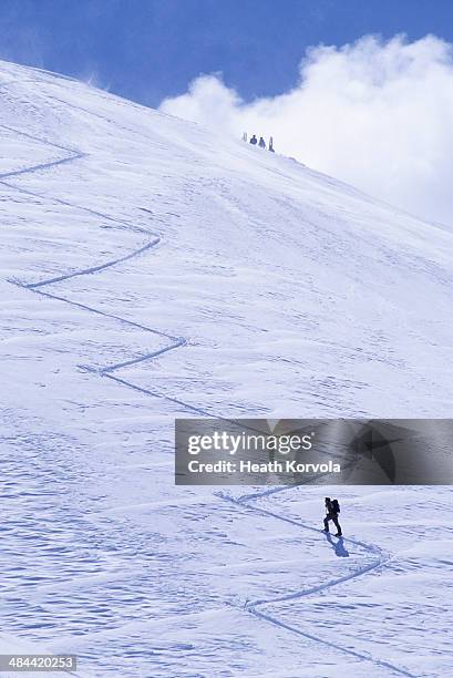 solo backcountry skier ascends skin track to peak. - mountain peak climb stock pictures, royalty-free photos & images