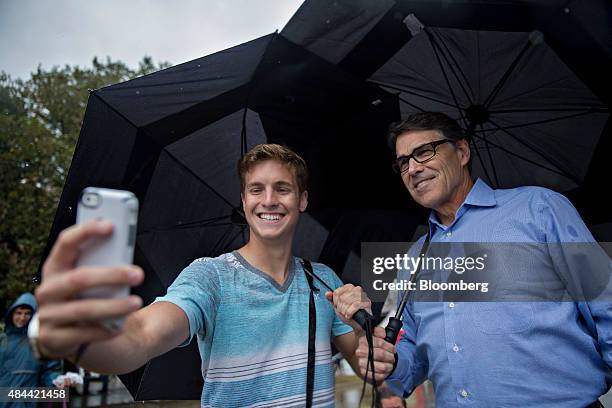 Rick Perry, former governor of Texas and 2016 Republican presidential candidate, stands for a selfie photograph with an attendee while holding an...