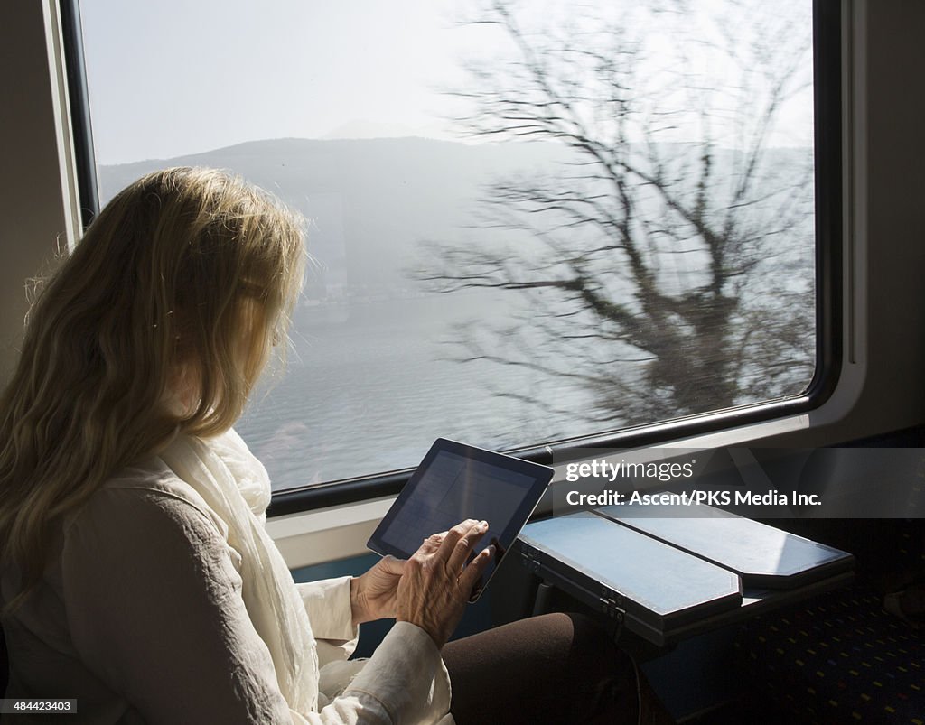 Woman uses digital tablet while riding on train