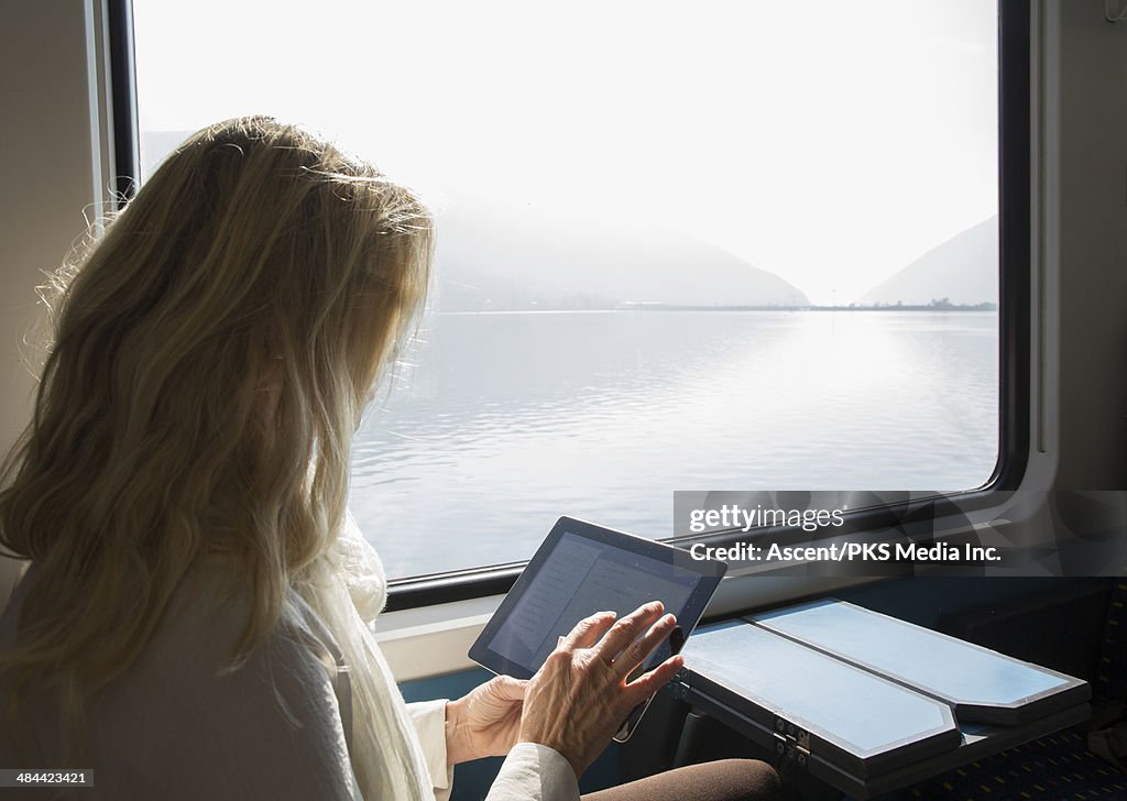 Woman uses digital tablet while riding on train