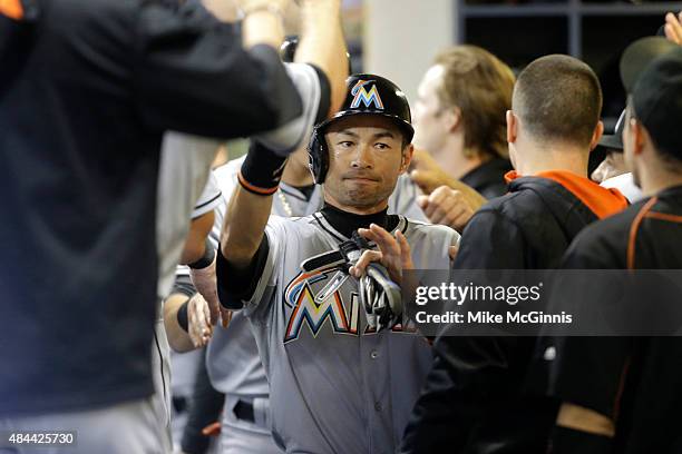 Ichiro Suzuki of the Miami Marlins celebrates in the dugout after reaching on a three RBI triple hit by Cole Gillespie in the first inning against...