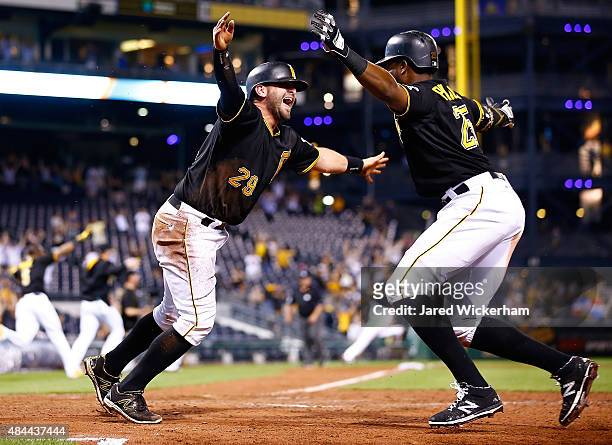 Francisco Cervelli of the Pittsburgh Pirates celebrates with teammate Gregory Polanco after sliding safely into home plate to score the game winning...