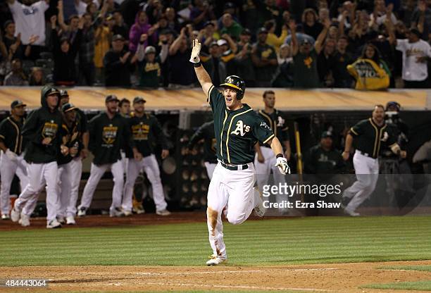 Mark Canha of the Oakland Athletics runs home to score the winning run on a hit by Billy Butler in the 10th inning of their game against the Los...