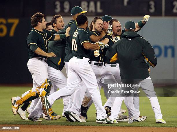 Billy Butler of the Oakland Athletics is surrounded by teammates after he hit in the winning run against the Los Angeles Dodgers in the tenth inning...