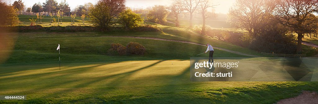 Leuchtendes Golfplatz mit Golfspieler auf dem putting green