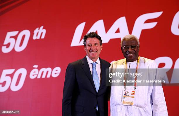 Newly elected IAAF president Lord Sebastian Coe stands with outgoing president Lamine Diack during the 50th IAAF Congress at the China National...