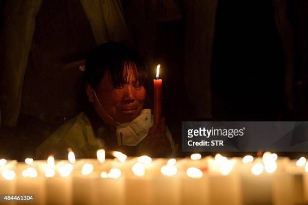To go with China-explosion-Tianjin-economy,FOCUS This picture taken on August 18, 2015 shows a woman holding candles while mourning for the victims...