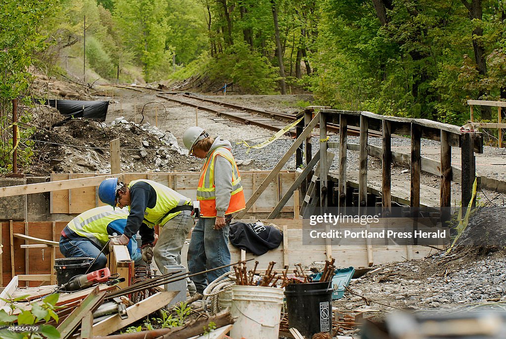 Workmen renovate an existing railroad bridge over Vaughn Brook in Hallowell as part of the construct
