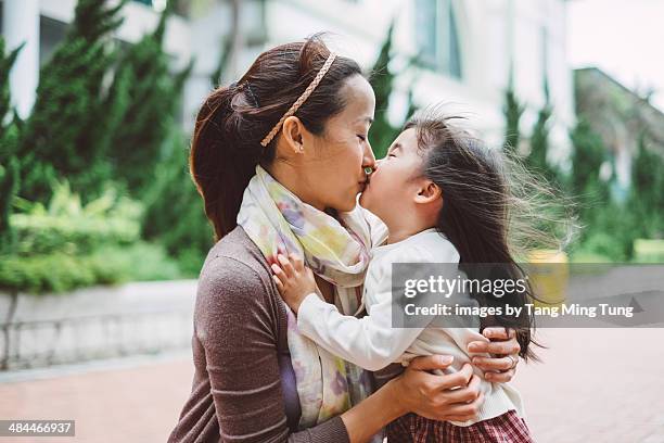 mom & toddler girl hugging & kissing joyfully - foulard vent photos et images de collection