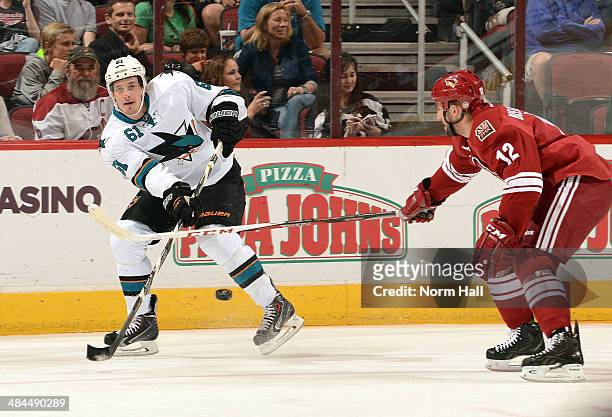Justin Braun of the San Jose Sharks passes the puck past the stick of Paul Bissonnette of the Phoenix Coyotes at Jobing.com Arena on April 12, 2014...