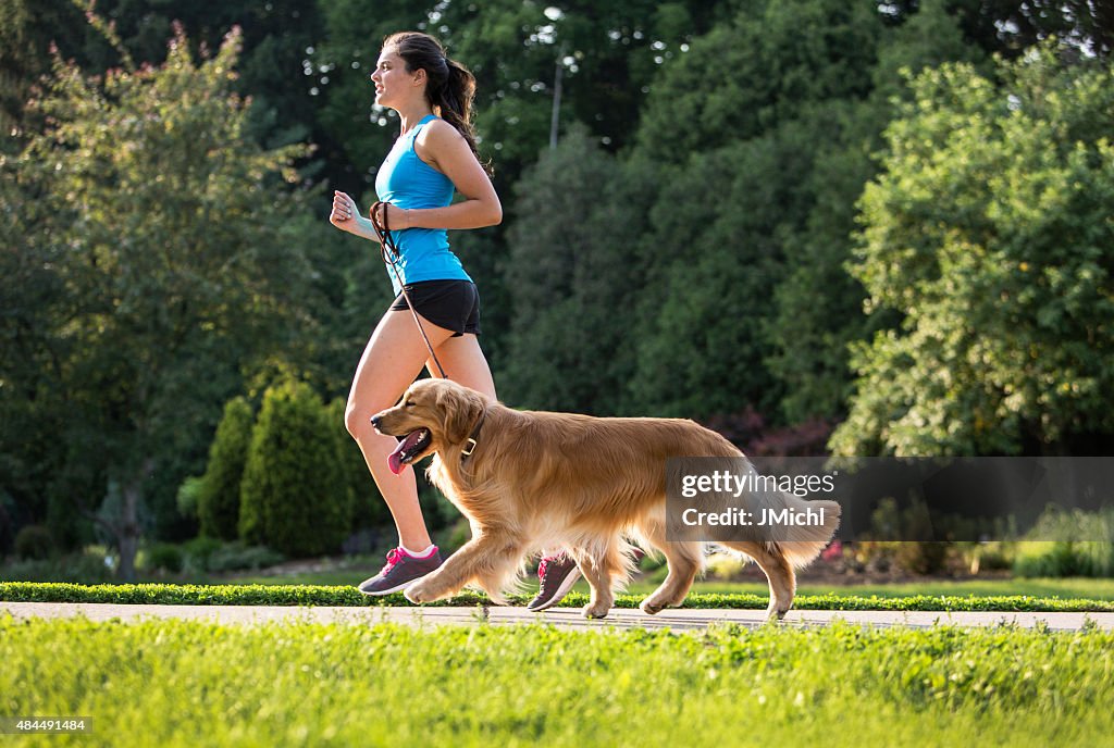 Jogger and Golden Retriever Running on a Paved Trail.