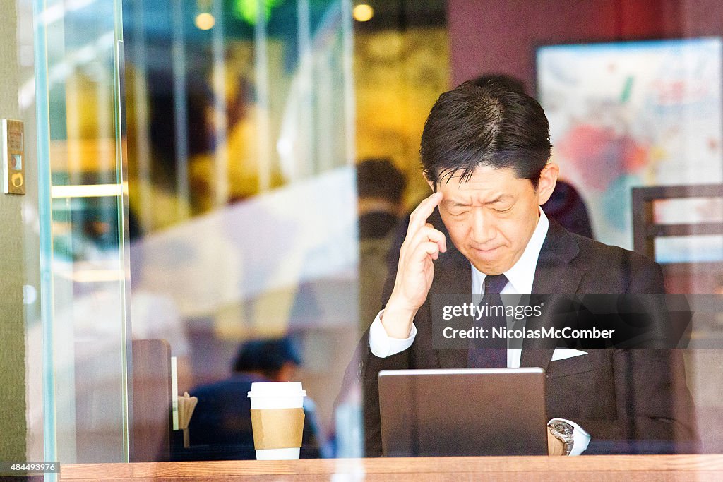 Pensive Japanese man in cafe trying to remember important information