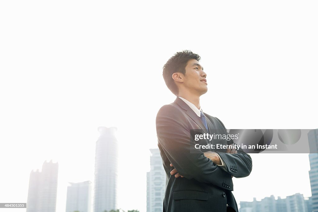 Businessman looking up with arms folded
